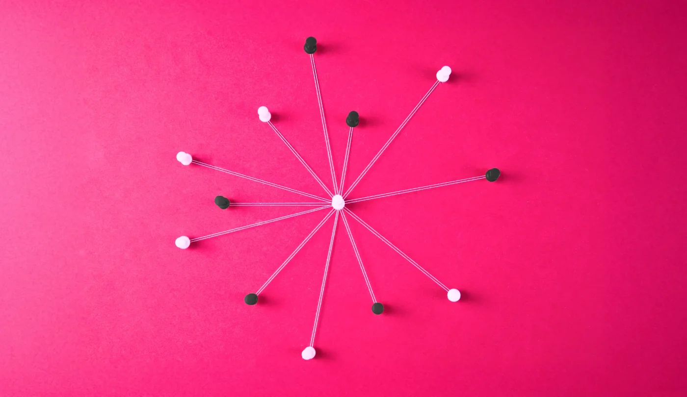 An abstract representation of a centralized network: a white pin at the center connects to multiple black and white pins around it using strings, symbolizing interconnected systems on a vibrant pink background.