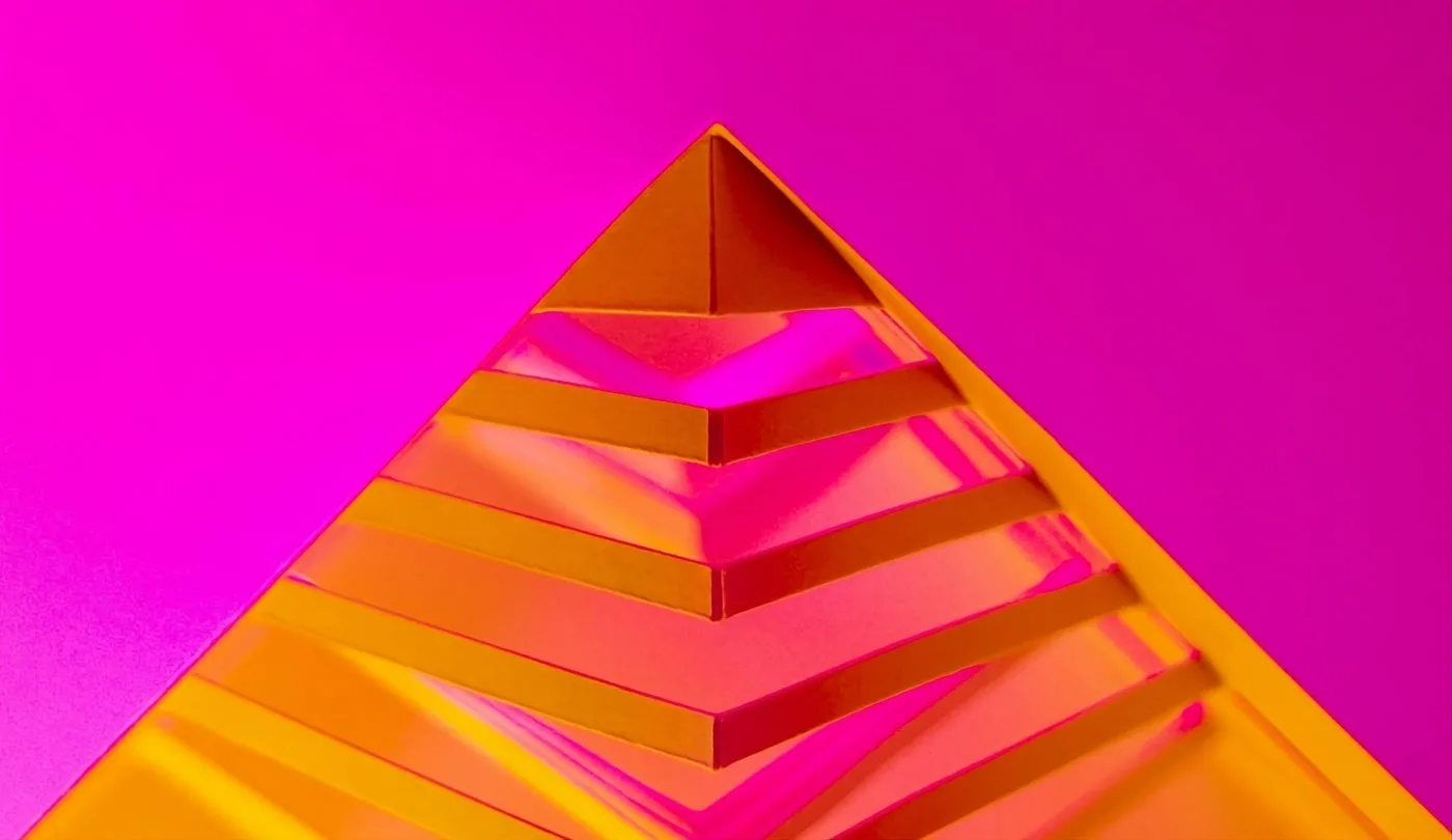 An eye-catching image featuring a bright magenta background with a 3D cut-out of an orange pyramid top in the foreground.